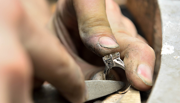 Jeweller repairing a gold ring. Focused on ring and fingers.