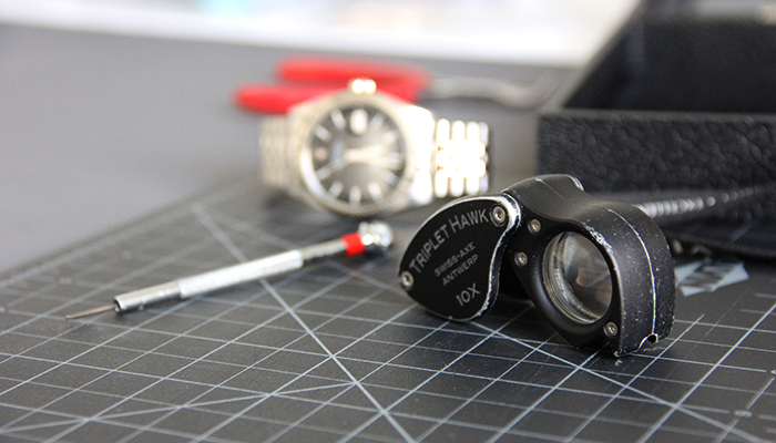 Jewelry loupe on workspace with a watch in the background