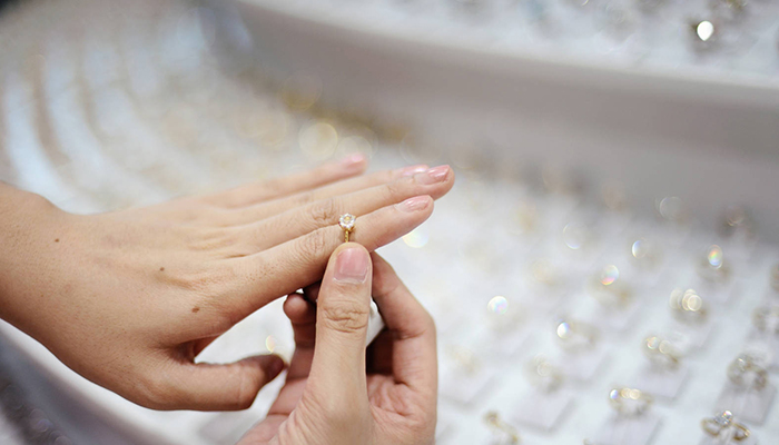 Woman trying on a diamond ring in a jewelry store. Image via Discover.