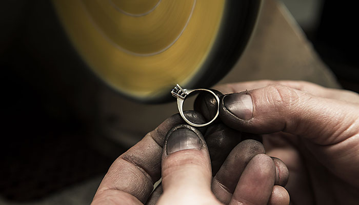 Jeweler is polishing a diamond ring with polishing machine.Speedlight was used for this image.