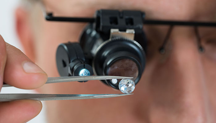 Close-up Of Person Looking At Diamond With Magnifying Loupe