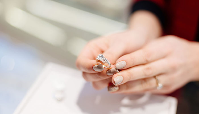 Female seller in a luxury jewelry store presents a ring. Buying a engagement ring. Jewelry store. Woman jeweler.