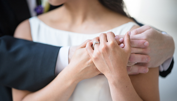 Couple hugging on wedding day with engagement ring visible