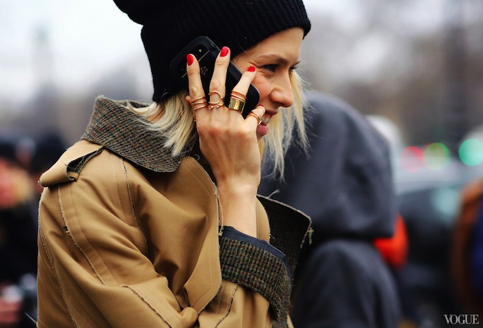 Fashion week street style of woman talking on phone with lots of rings and jewelry