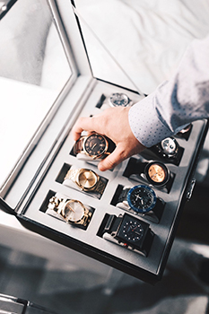 A man reaching into a watch collection box