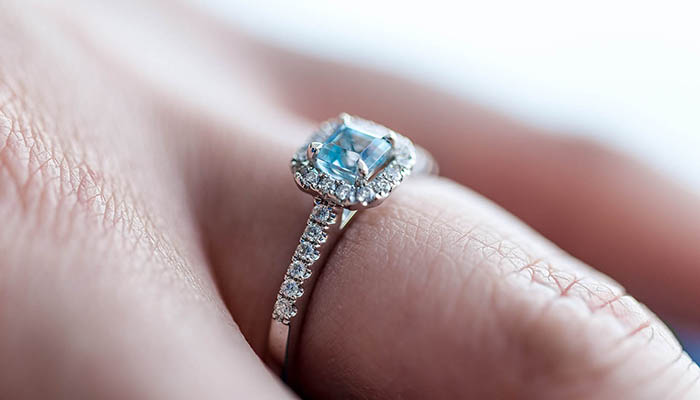 Engagement ring with blue center stone, on finger