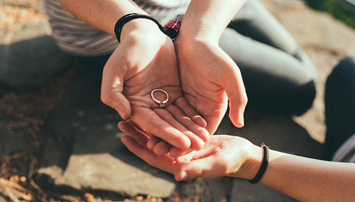 Couple holding engagement ring in hands